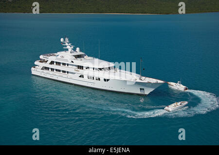 Superyacht di lusso ancorato nelle acque turchesi con piccole barche nelle vicinanze Foto Stock