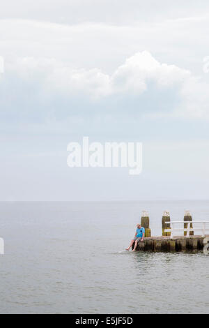 Paesi Bassi, Den Oever, IJsselmeer Dam anche chiamato Afsluitdijk. L'uomo pagaiando sul molo Foto Stock