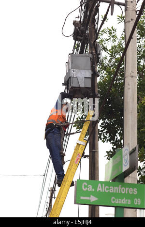 LIMA, Perù - Luglio 23, 2013: Unidentified uomo in piedi sulla scaletta e lavorando su cavi e una casella su un lampione Foto Stock