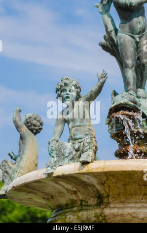 Una Figurina bambino alza il suo braccio sul perimetro di una fontana urbano Foto Stock