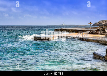 Vista di S'Algat beach in Menorca con il faro in background, isole Baleari, Spagna Foto Stock