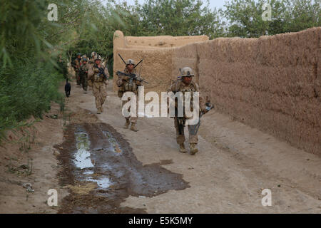 Marines americani con il Primo Battaglione, 7° Reggimento Marine, il pattugliamento lungo una parete del villaggio durante una missione Luglio 4, 2014 in Gereshk, provincia di Helmand, Afghanistan. Foto Stock