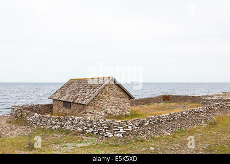 Vecchio boathouse con muro di pietra sulla riva Foto Stock