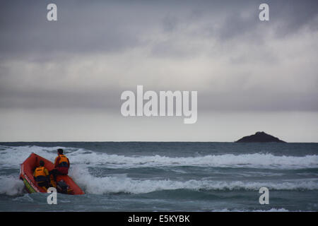 Barca gonfiabile con 2 bagnini scouting costa in Dunedin annuali di midwinter tuffo polare tenutosi presso il St Clair Esplanade Foto Stock