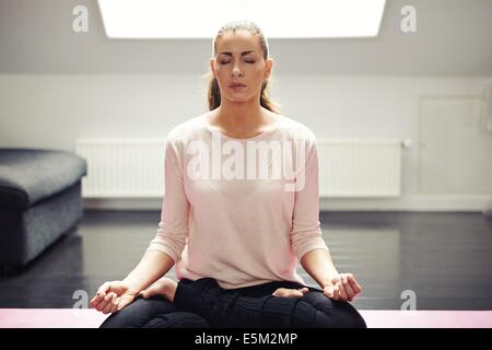 Ritratto di donna bella esercitazione. In un momento di relax a casa con lo yoga allenamento. Montare caucasian modello femminile nella meditazione. Foto Stock