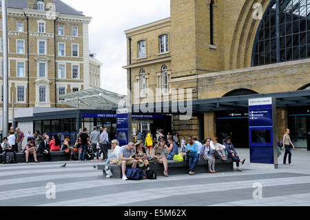 La gente seduta in Kings Cross Station Square, Londra Inghilterra Gran Bretagna REGNO UNITO Foto Stock