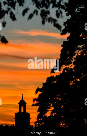 Silhouette della chiesa e ad albero contro il cielo drammatico Foto Stock