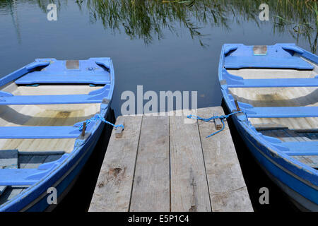 Blu e bianco imbarcazioni a remi al fianco di un molo e per il noleggio al Molo Lisloughery,Cong sulle rive del Lough Corrib, Irlanda. Foto Stock