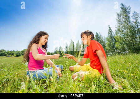 I bambini giocano sasso-carta-forbici sull'erba Foto Stock