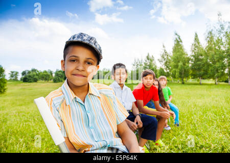 Cinque bambini felici sedere sulle sedie in fila all'aperto Foto Stock