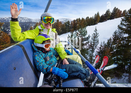 Felice mamma e bambino in maschere da sci sul sedile ascensore Foto Stock