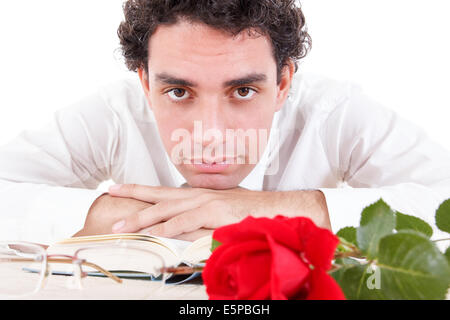 Uomo di relax con fiore e buon libro con gli occhiali a parte, romantico studiando, riflessivo uomo appoggiato su di un libro con rose e gla Foto Stock