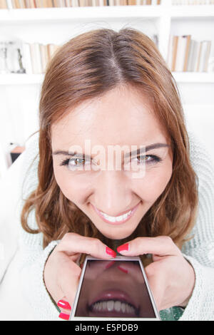 Giovane donna con crazy face expression è il tentativo di nonostante insidiosamente con un telefono cellulare tramite un messaggio o una chiamata, applicazioni illegali f Foto Stock