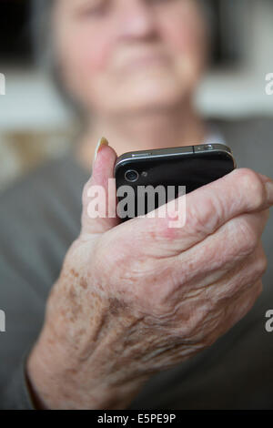 Donna anziana tenendo uno smartphone Foto Stock