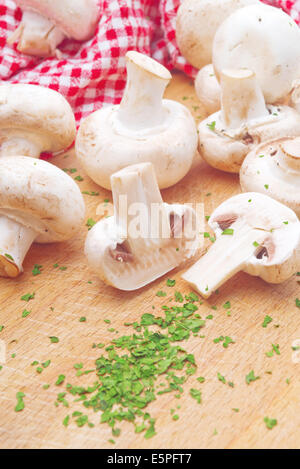 Fresca Portabello commestibile Fungo Champignon e fresco verde di prezzemolo tritato sul tavolo da cucina. Funghi saltati con prezzemolo mea Foto Stock