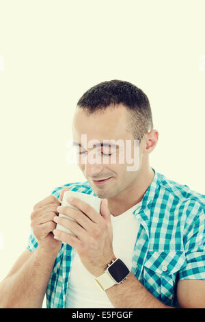 Felice giovane godendo bevande calde e odore di caffè, bello ragazzo holding tazza di caffè o di tè godendo il profumo del caffè Foto Stock