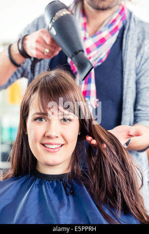 Parrucchiere asciugare i capelli donna in negozio Foto Stock