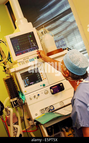 Anestesista rianimatore in abito chirurgico a fianco di anestetico apparecchiature di monitoraggio durante la chirurgia. Foto Stock