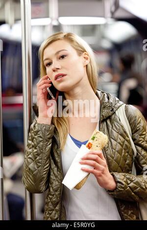 Donna di mangiare un panino in metropolitana. Foto Stock