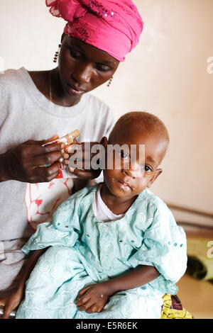 L'appetito test : donna dando il suo bambino una razione di plumpy dado di arachidi terapeutico a base di Programma alimentare di trattamento ambulatoriale di Foto Stock