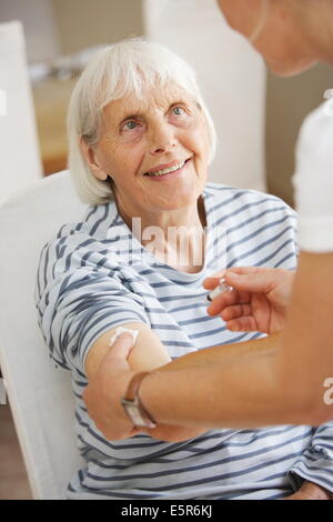 80 anno vecchia donna riceve la vaccinazione contro l'influenza. Foto Stock