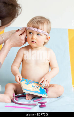 La misurazione della circonferenza di un 14-mese-vecchio la testa del bambino (perimetro cranica) con un nastro di misurazione. Foto Stock