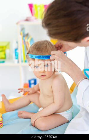 La misurazione della circonferenza di un 14-mese-vecchio la testa del bambino (perimetro cranica) con un nastro di misurazione. Foto Stock