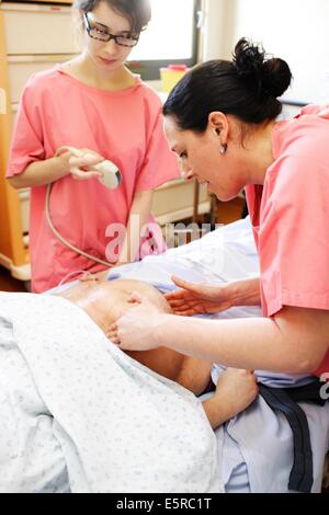 Donna in fase di monitoraggio fetale dopo un'ostetrica appena eseguito una versione, una procedura di ostetricia in cui la posizione Foto Stock