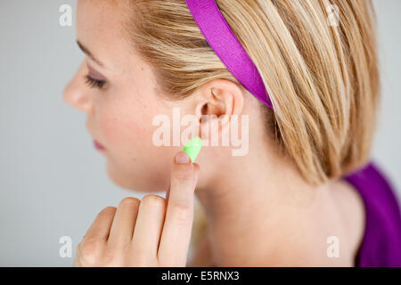 Donna che indossa i tappi per le orecchie. Foto Stock