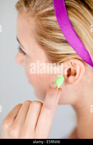 Donna che indossa i tappi per le orecchie. Foto Stock