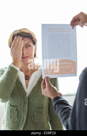 Senior donna guardando una Griglia di Amsler per rilevare la degenerazione maculare. Foto Stock