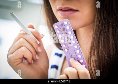 Donna che mantiene la contraccezione orale pillole e sigaretta. Foto Stock