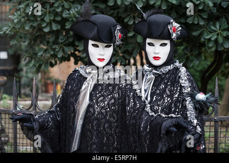 2 Donne in identiche stilizzata costumi settecenteschi di nero con argento dalla chiesa di San Zaccaria durante il Carnevale di Venezia. Foto Stock