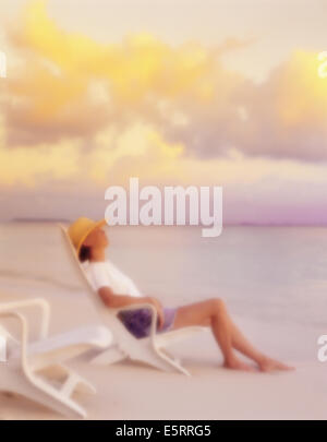 Donna relax sulle sdraio sulla spiaggia in riva al mare su Bandos Island, North Male Atoll, Maldive Foto Stock