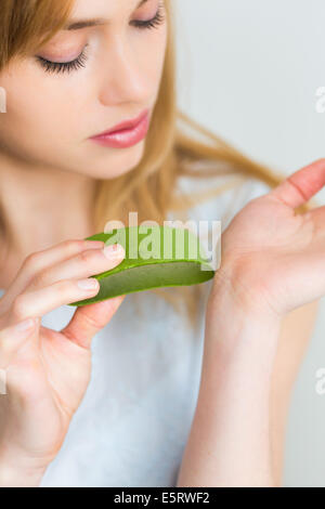 Donna applicando una foglia di aloe vera sulla pelle Foto stock - Alamy