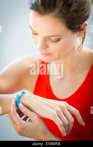 Donna che indossa un UP® di Jawbone braccialetto elettronico, sensore tracker. Foto Stock