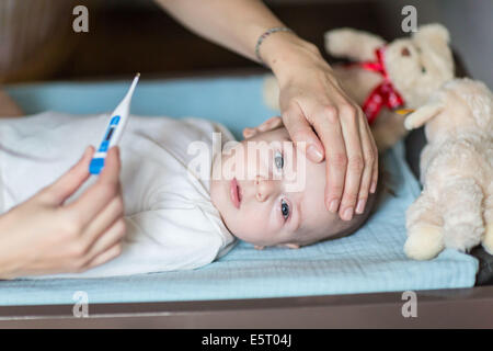 Madre controllando la temperatura del suo vecchio di 4 mesi fervono baby boy con un termometro digitale. Foto Stock