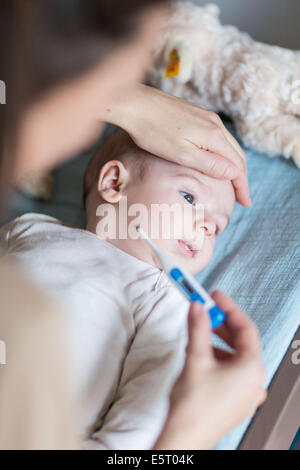 Madre controllando la temperatura del suo vecchio di 4 mesi fervono baby boy con un termometro digitale. Foto Stock