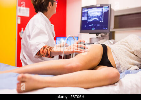 Paziente di sesso femminile subendo un doppler a ultrasuoni (angiodynography) scansione degli arti inferiori, Angoulême ospedale, Francia . Foto Stock