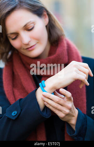 Donna che indossa un UP® di Jawbone braccialetto elettronico, sensore tracker. Foto Stock