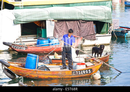 L'uomo le piastre una piccola barca in Causeway Bay Typhoon Shelter, Hong Kong. Foto Stock