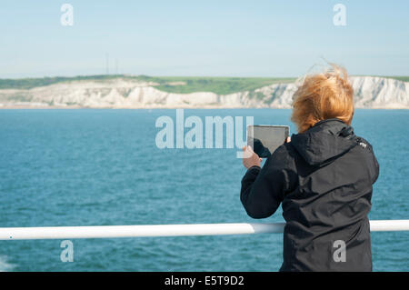 Il passeggero scattare una fotografia delle Scogliere Bianche di Dover con una compressa dal traghetto sulla Manica Foto Stock