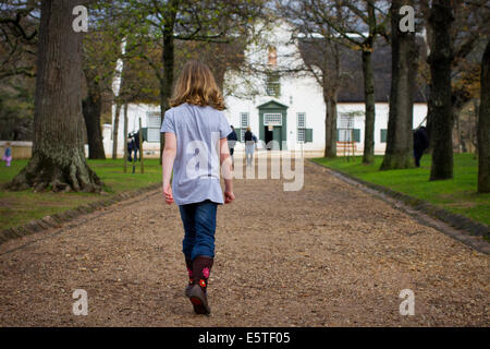 Una ragazza camminare lungo il viale che conduce a un grand Cape Dutch a Groot Constantia Foto Stock