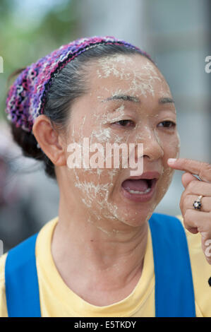 Un'anziana donna tailandese utilizzando erbe naturali e miscela di foglia per proteggere il suo volto da Sun Foto Stock