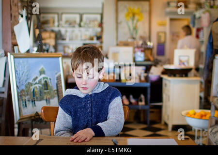 Giovane ragazzo in una tabella in un negozio d'arte / ristorante Foto Stock