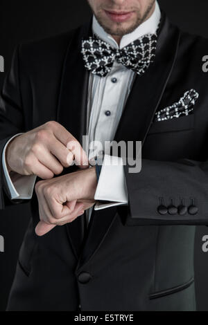 Uomo in uno smoking avvolge orologi Foto Stock