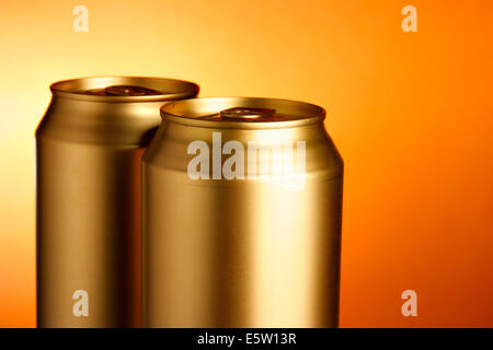 Golden lattine di birra close-up su sfondo arancione Foto Stock