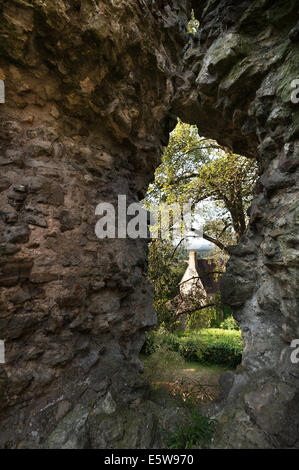 Vista attraverso la finestra del muro di castello al di sopra del weald del Kent con arco in pietra e cottage in primo piano Foto Stock