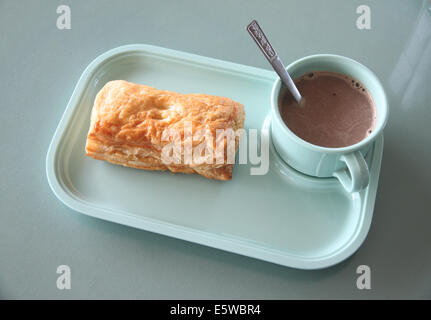 Patty e cioccolata calda in un piatto blu sul tavolo da pranzo. Foto Stock