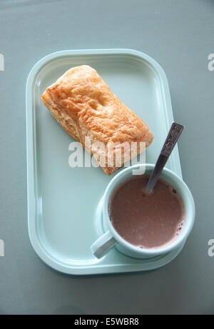 Patty e cioccolata calda in un piatto blu sul tavolo da pranzo. Foto Stock